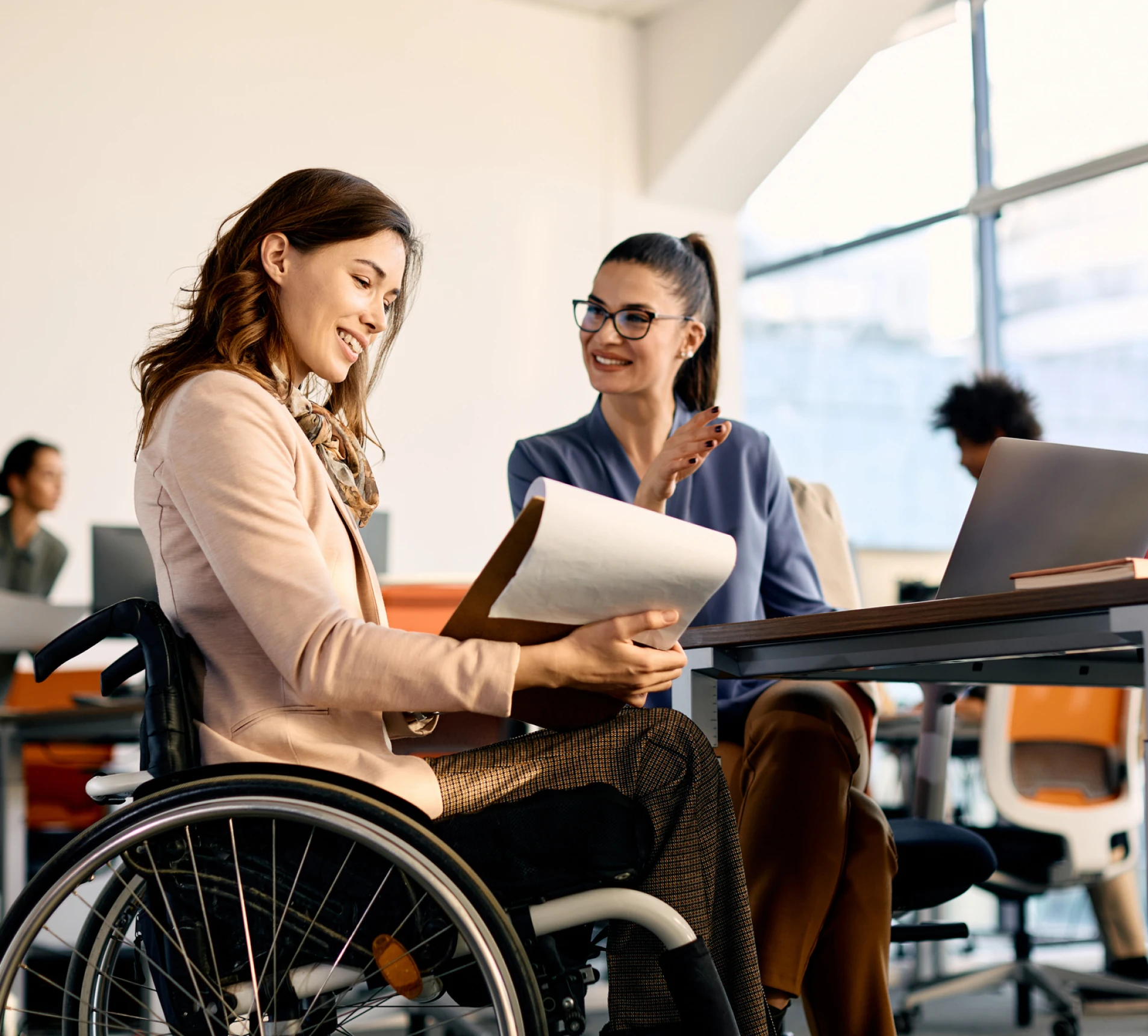 Woman in wheelchair discussing with colleague