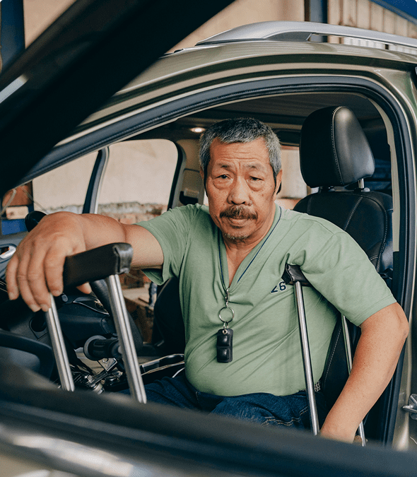 Man with crutches sitting in car