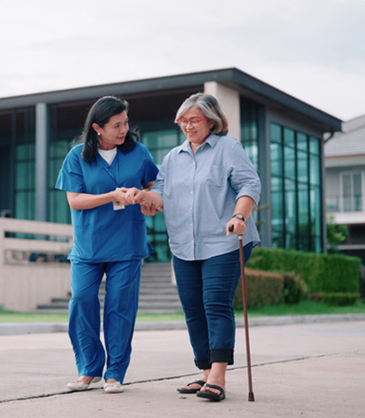 A caregiver assists an elderly woman with walking.