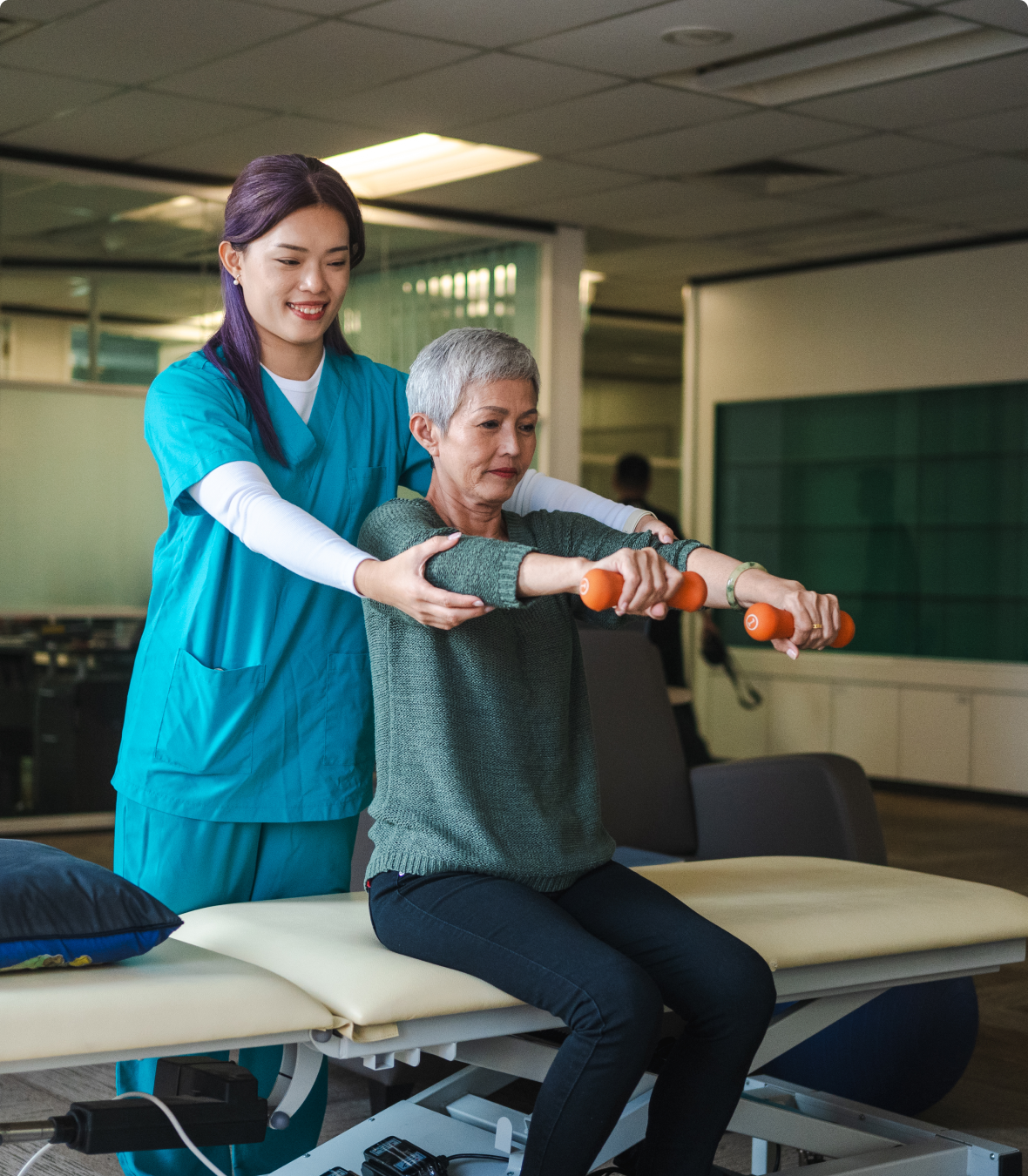 Physical therapist assisting elderly man with arm exercises using weights.