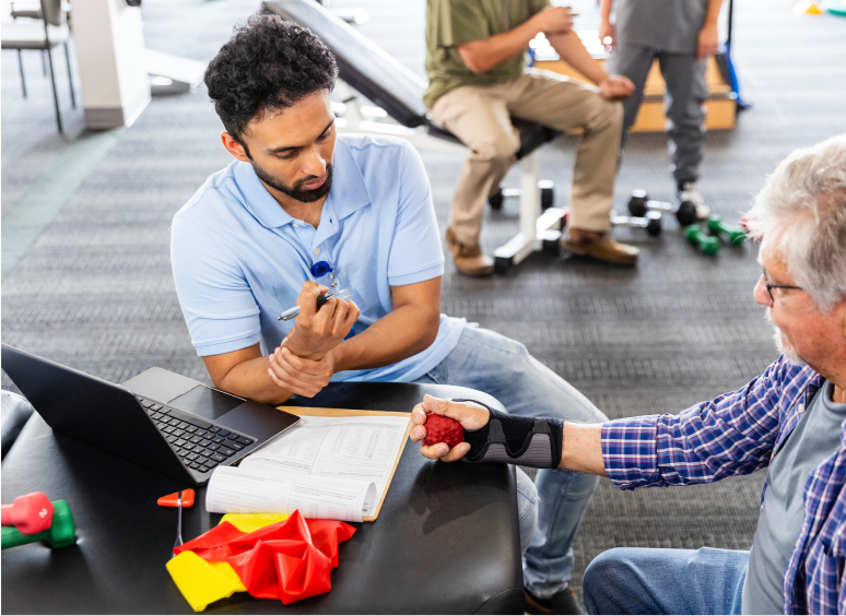 Two people exchanging a handshake over a table with papers and tools.