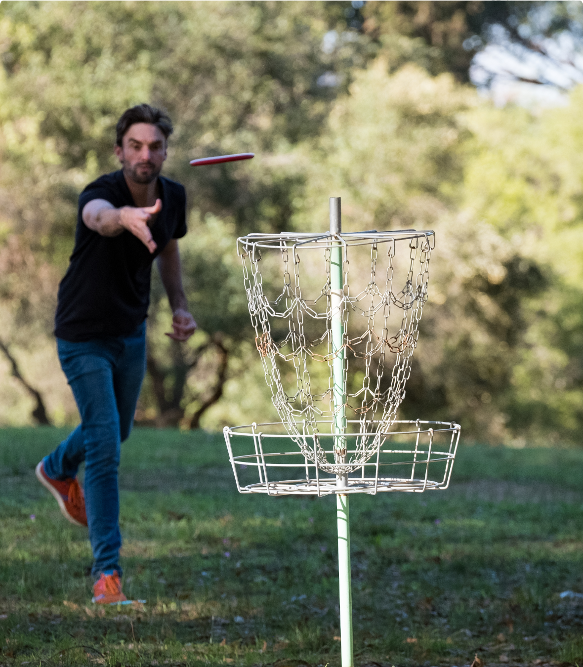 A man playing disc golf aiming at the basket.