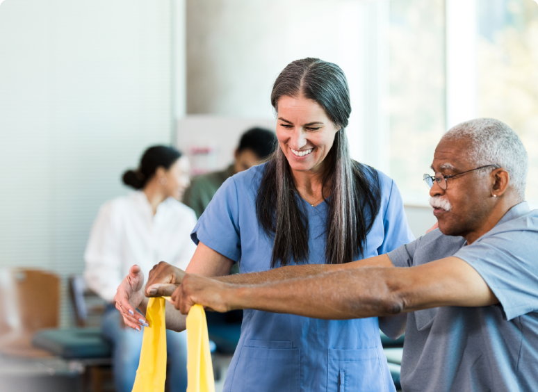 A therapist assists an elderly man with resistance band exercises.