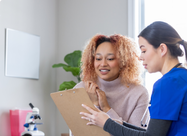 Two women collaborating over a clipboard in a bright office space.